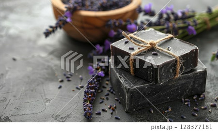 Natural black soap tied with twine and lavender flowers. Organic skincare product on dark background. 128377181