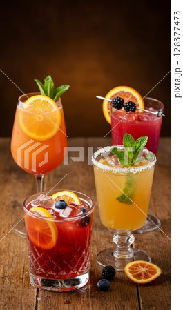 Assorted fresh fruit cocktails on wooden table with citrus garnish 128377473