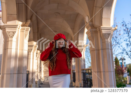 Beret Fashion Woman: Woman adjusts beret under arched walkway, sunny day for photoshoot or style shoot. 128377570