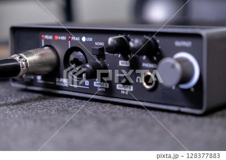 Black audio interface displays illuminated USB and Peak indicators, with multiple input, output, and control knobs for music production and recording 128377883