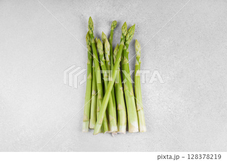 Pile of fresh raw green asparagus or sparrowgrass stems on light textured background Pile of fresh raw green asparagus or sparrowgrass stems on light textured background 128378219