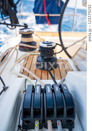 Close-up of rope clutches and winches on the deck of a sailing yacht near Croatia. Sailing equipment, control systems and technical detail of life at sea. Close-up of rope clutches and winches on the deck of a sailing yacht near Croatia. Sailing equipment, control systems and technical detail of life at sea. 128379292