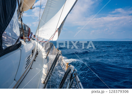 Side of a sailing yacht cutting through the sea with full sails near Croatia. Motion, freedom, sailing lifestyle and adventure on the open water. 128379306
