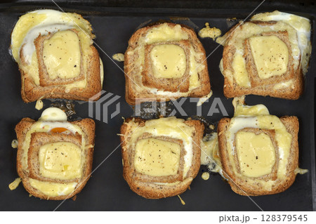 Baked egg-in-toast with melted cheese Baked egg-in-toast with melted cheese 128379545