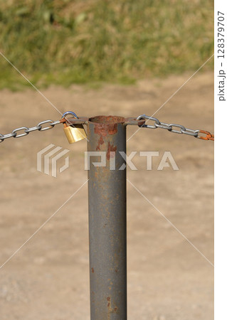 Metal post with a chain and padlock Metal post with a chain and padlock 128379707