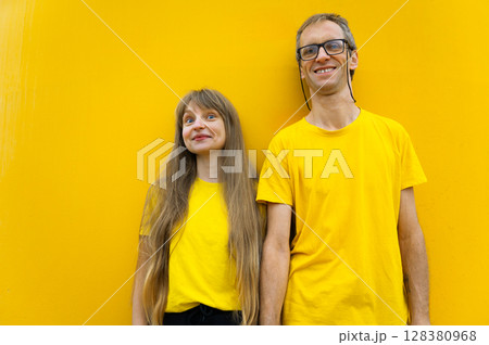 Man and Woman in Yellow Outfits Smiling Against a Matching Yellow Background Man and Woman in Yellow Outfits Smiling Against a Matching Yellow Background 128380968