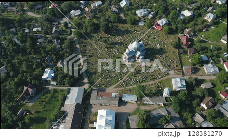 Aerial view of the church and graveyard in the village. Rustic wooden church in the center of the countryside. Rows of burials are located around the temple. Aerial view of the church and graveyard in the village. Rustic wooden church in the center of the countryside. Rows of burials are located around the temple. 128381270