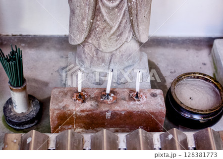 お地蔵様の足もとにロウソクと線香が置かれている風景 お地蔵様の足もとにロウソクと線香が置かれている風景 128381773