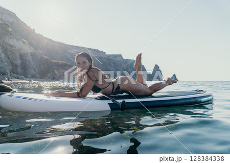 Woman Paddleboard Ocean - Young woman enjoys a paddleboard session in the ocean. Woman Paddleboard Ocean - Young woman enjoys a paddleboard session in the ocean. 128384338