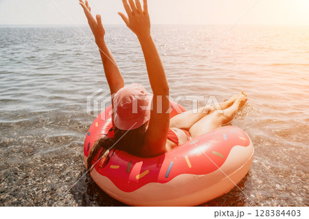 Woman, Beach, Inflatable, Smiling woman floats on an inflatable ring in the ocean on a sunny day. Woman, Beach, Inflatable, Smiling woman floats on an inflatable ring in the ocean on a sunny day. 128384403