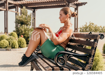Woman Laptop Bench Park - Working outdoors on a sunny day, woman sitting on a bench with a laptop. 128384405