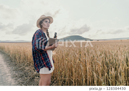Young Woman in a Wheat Field with a Tablet 128384430