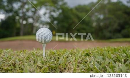 Golf clubs and golf balls on a green lawn in a beautiful golf course with morning sunshine. 128385148