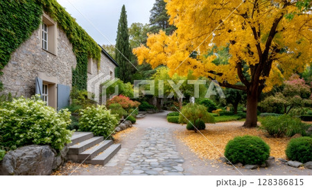 Stone house with ivy and golden autumn tree in peaceful garden 128386815