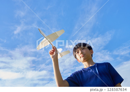 青空に向かって模型飛行機を飛ばす少年 128387634