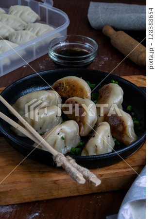 Fried Japanese pork gyoza served on cast iron pan with dipping soy sauce and chopsticks placed on napkin traditional Asian dumplings close up food photography top view Fried Japanese pork gyoza served on cast iron pan with dipping soy sauce and chopsticks placed on napkin traditional Asian dumplings close up food photography top view 128388654