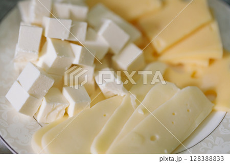 White Feta Cheese Cubes with Yellow Cheese Slices on Plate 128388833