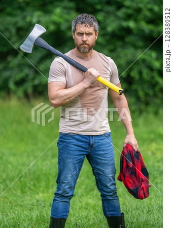 Lumberjack men in forest with axe. Lumberjack carries axe. Forest silence. Handsome man with axe. Lumberjack in woods with an ax. Lumberjack in shirt with heavy axe. Strong man work in forest 128389512