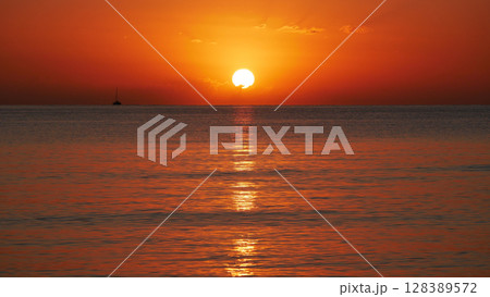 Vivid sunset over the sea with a glowing sun and golden reflection on the calm water. Peaceful and captivating atmosphere. Nature background, relaxation concept, travel theme and inspirational visual Vivid sunset over the sea with a glowing sun and golden reflection on the calm water. Peaceful and captivating atmosphere. Nature background, relaxation concept, travel theme and inspirational visual 128389572
