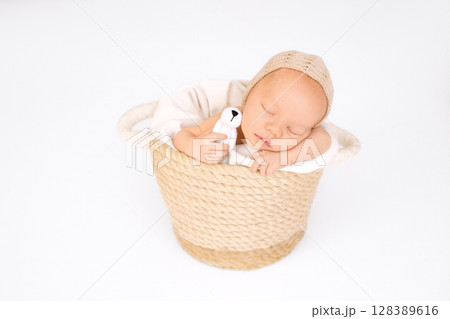 Photo of a newborn baby in a basket with knitted toy dog in  hand. 128389616