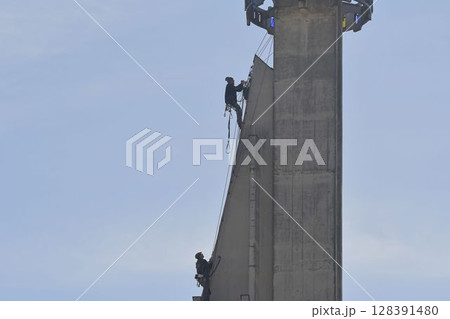 Craftsmen repair the tower of a modern church. Roofers fix the tower of a modern building. The concept of working at heights and work safety 128391480