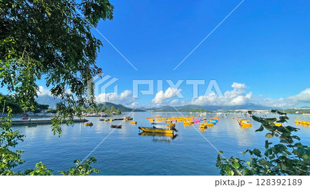 Fishing, recreational boats on bay, natural background with trees, clouds, blue sky and mountains 128392189