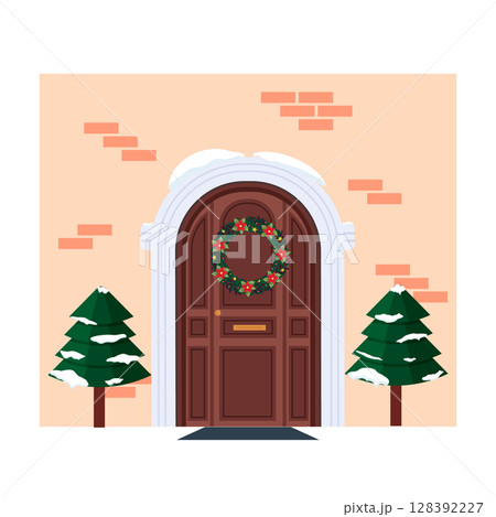 Fragment of the house facade with a door and a Christmas wreath. Christmas trees at the entrance. Brick facade. Festive atmosphere and anticipation of Christmas and New Year. Winter festive decoration 128392227