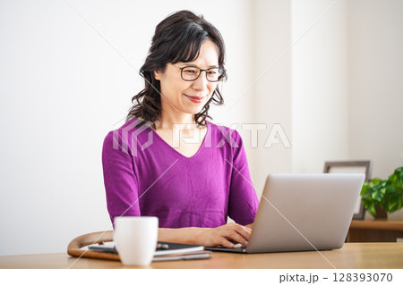 家のリビングでテレワークをする50代のミドル女性 128393070