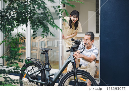 家の庭先で自転車を手入れする夫と話す妻 128393075