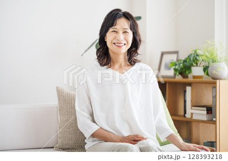家のリビングでソファーに座る50代ミドル女性のポートレート 128393218