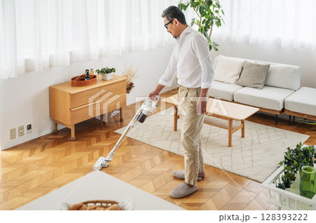 家のリビングを掃除する50代のミドル男性 家のリビングを掃除する50代のミドル男性 128393222