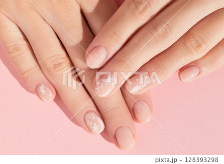 Beautiful womans hands with nude nail design on pink background. Manicure, pedicure beauty salon concept Beautiful womans hands with nude nail design on pink background. Manicure, pedicure beauty salon concept 128393298