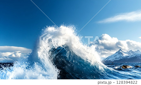 A powerful turbulent seascape with crashing waves and sea spray against a backdrop of a cloudy blue sky 128394822