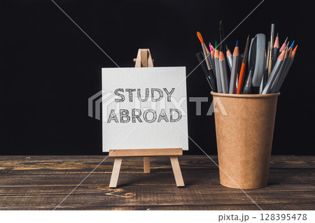 A white sign that says Study Abroad is on a wooden table 128395478