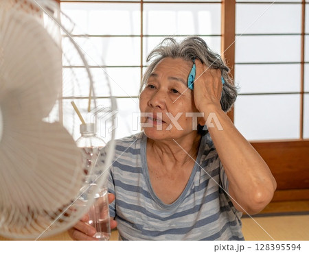 扇風機の前で汗を拭く日本人の高齢女性5　AI生成画像 128395594