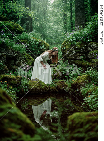 森の泉を覗き込む白いドレスの女性の幻想的な姿 森の泉を覗き込む白いドレスの女性の幻想的な姿 128396294