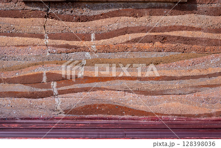 Full frame shot of an earthen wall texture of clay house structure. These walls are constructed by ramming a mixture of aggregates, including gravel, sand, silt and a small amount of clay. Full frame shot of an earthen wall texture of clay house structure. These walls are constructed by ramming a mixture of aggregates, including gravel, sand, silt and a small amount of clay. 128398036