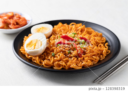 Spicy korean dried instant noodles with boiled egg, scallion, sesame seed, chili and kimchi Spicy korean dried instant noodles with boiled egg, scallion, sesame seed, chili and kimchi 128398319