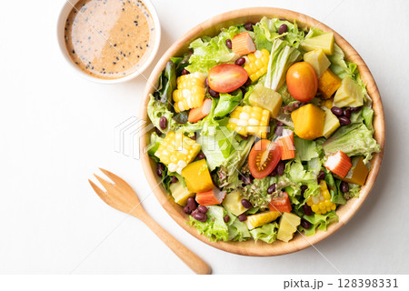 Top view of colorful vegetable salad in a rustic wooden bowl with Japanese sesame dressing  128398331