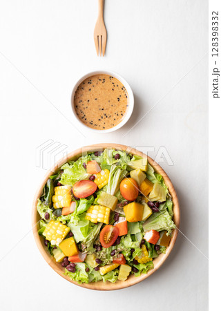 Top view of colorful vegetable salad in a rustic wooden bowl with Japanese sesame dressing  128398332