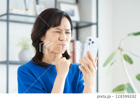 スマホで悩むミドルの女性 スマホで悩むミドルの女性 128399282