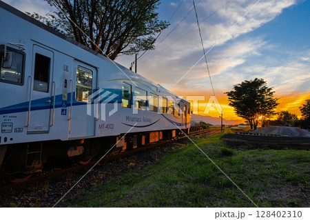 夕焼け光芒に映える田園を走る鉄道列車風景　(見晴台駅)(南阿蘇村) 128402310