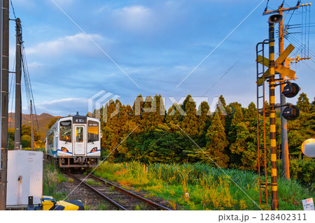 夕焼け光芒に映える田園を走る鉄道列車風景　(見晴台駅)(南阿蘇村) 128402311