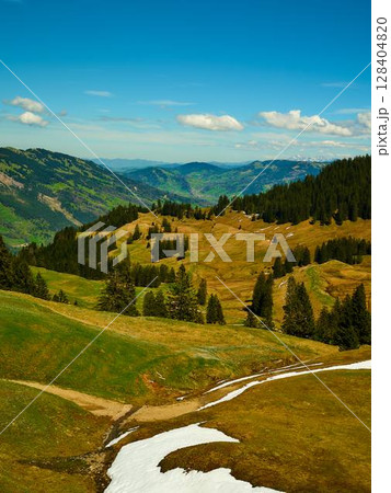 Beautiful green hills and valleys under a clear blue sky with scattered clouds in a mountainous region 128404820