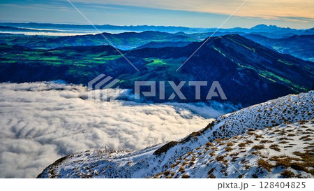 Breathtaking view from mountain peak overlooking valley shrouded in clouds at dawn 128404825