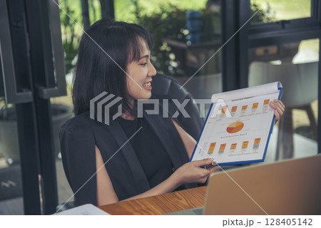 Asian businesswoman vdo call conference telecommunicate office desk. Women show Graph business report online meeting. Freelance women using laptop home office technology. Businesswoman online meeting 128405142