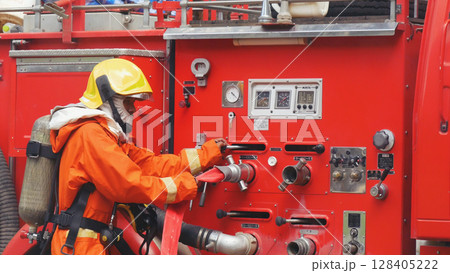 Fireman prepare equipment fighting extinguisher at fire engine truck. Firefighter fighting with smoke flame using fire hose, tube, chemical water foam spray at truck. Fireman wear hard hat protection 128405222