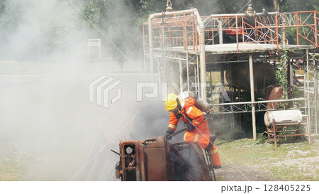 Firefighter fighting smoke flame use fire hose chemical water foam spray engine. Firefighter Rescue training in fire fighting extinguisher. Fireman wear hard hat safety suit uniform for protection Firefighter fighting smoke flame use fire hose chemical water foam spray engine. Firefighter Rescue training in fire fighting extinguisher. Fireman wear hard hat safety suit uniform for protection 128405225
