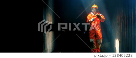 Firefighter Rescue training in fire fighting extinguisher. Firefighter fighting with flame using fire hose chemical water foam spray engine. Fireman wear hard hat, safety suit uniform for protection 128405228