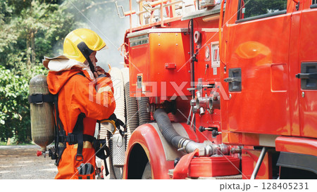 Fireman prepare equipment fighting extinguisher at fire engine truck. Firefighter fighting with smoke flame using fire hose, tube, chemical water foam spray at truck. Fireman wear hard hat protection 128405231